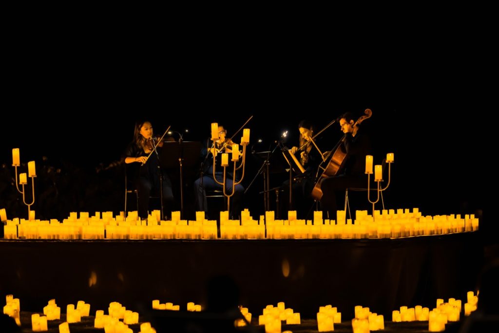 a string quartet performing on stage surrounded by hundreds of candles at Jacob's Creek