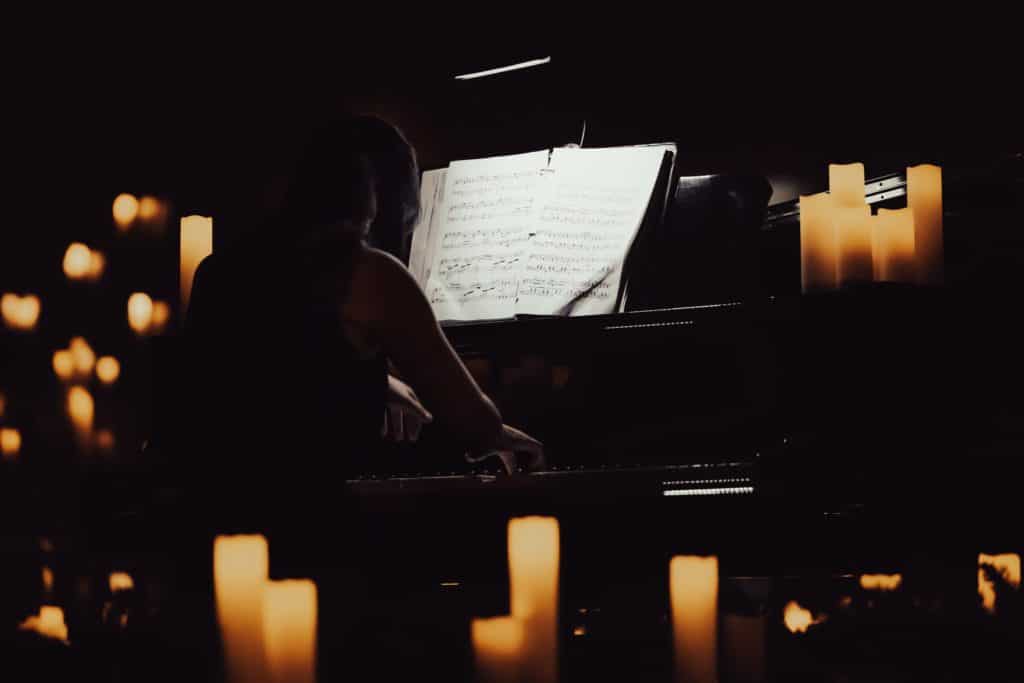 close up of pianist performing at a candlelight concert showing grand piano and sheet music