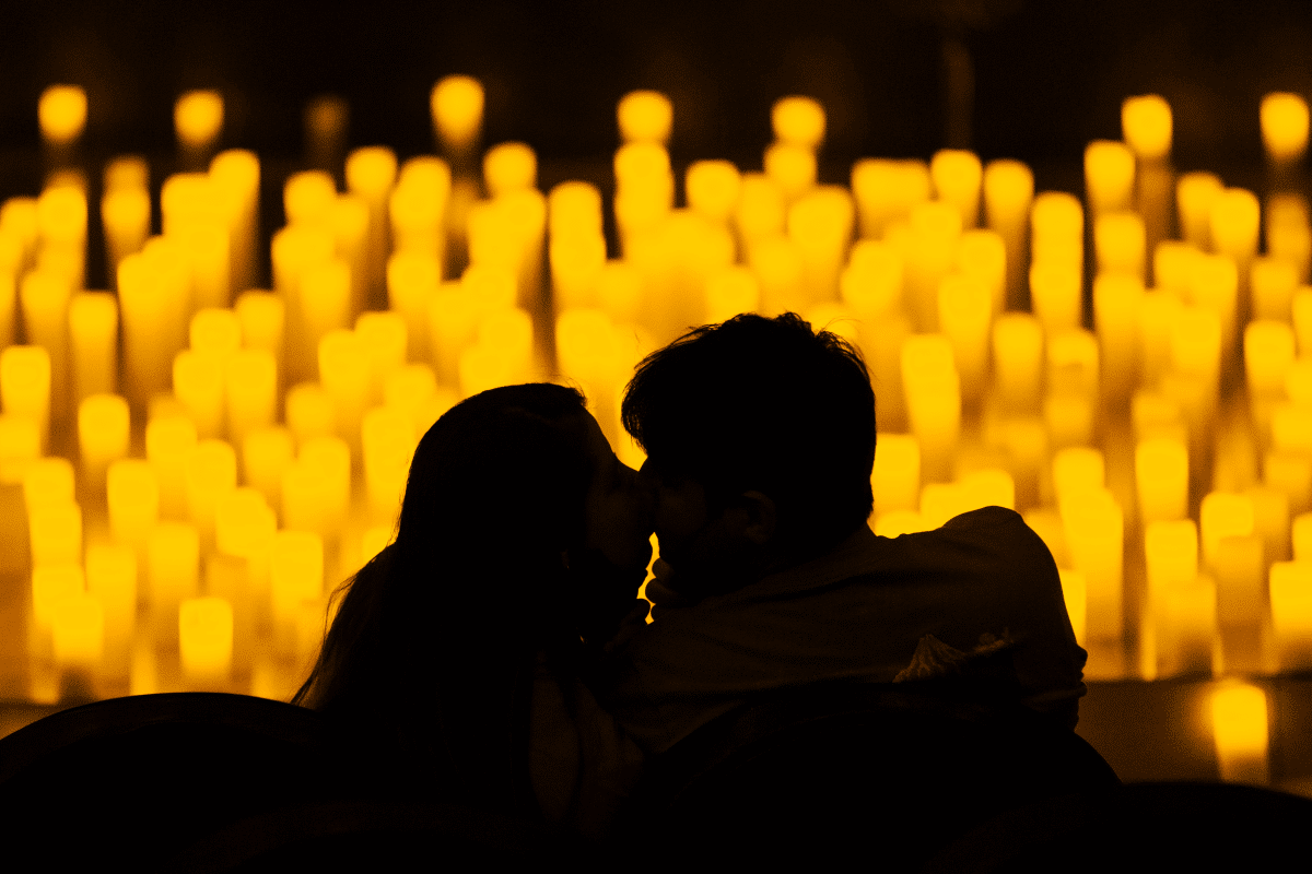 A silhouette of a couple with a sea of candles in front of them.