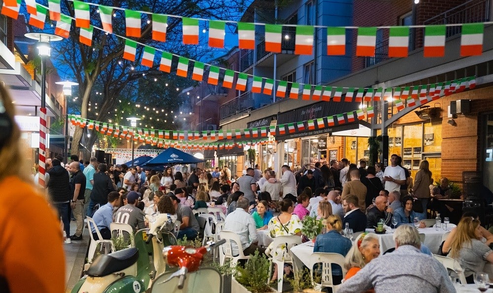 Laneway closed off with street seating and Italian flags hovering above the festival