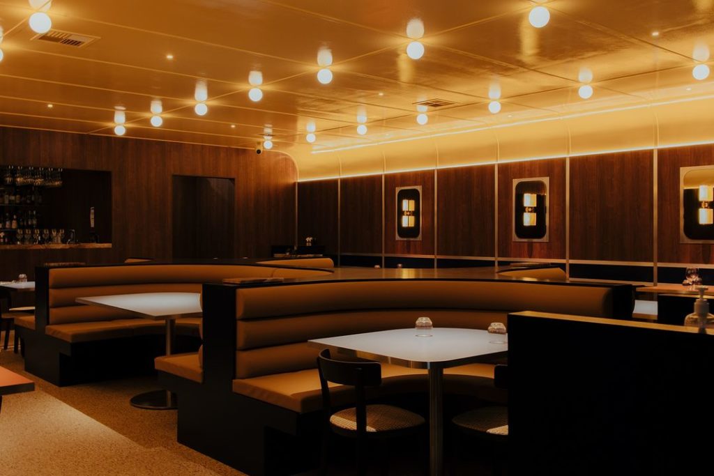 Slick restaurant interior with dim lighting, cushioned booths, gold detail