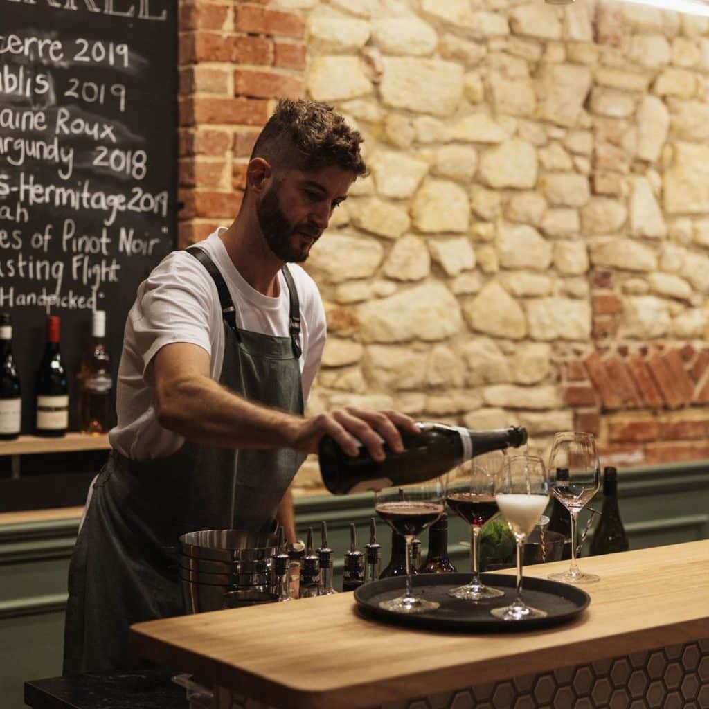 Waiter pouring wine, exposed stone wall backdrop