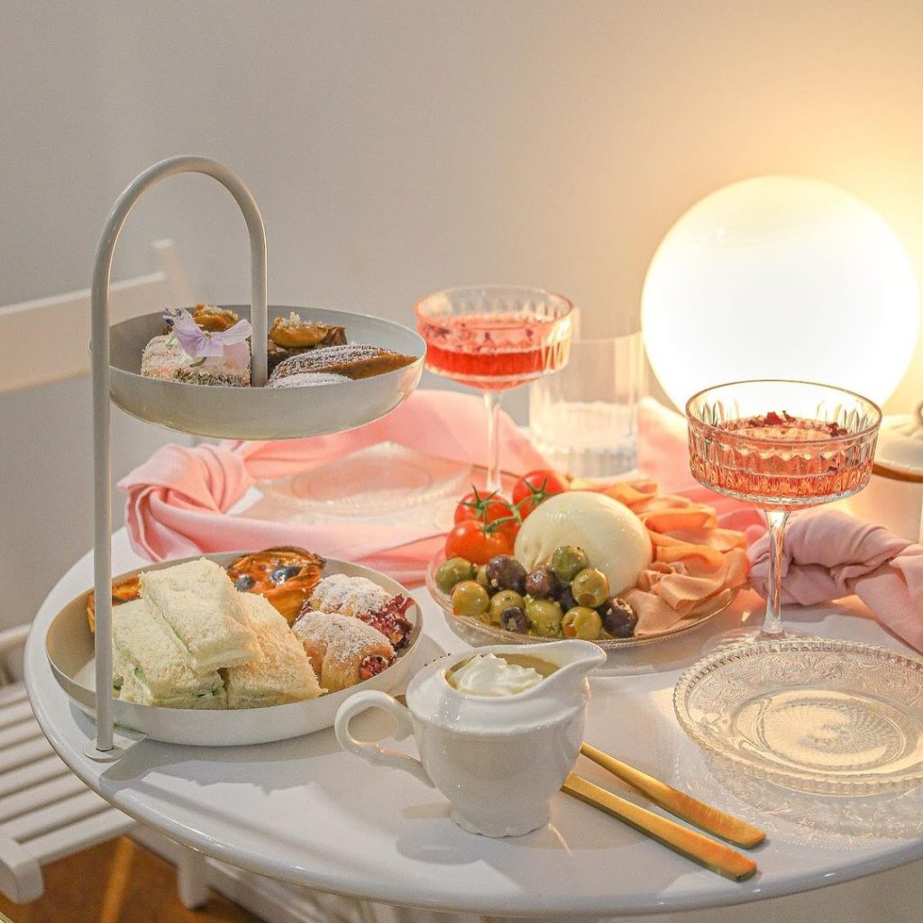 Curated spread of high tea items, cocktails, ambient light