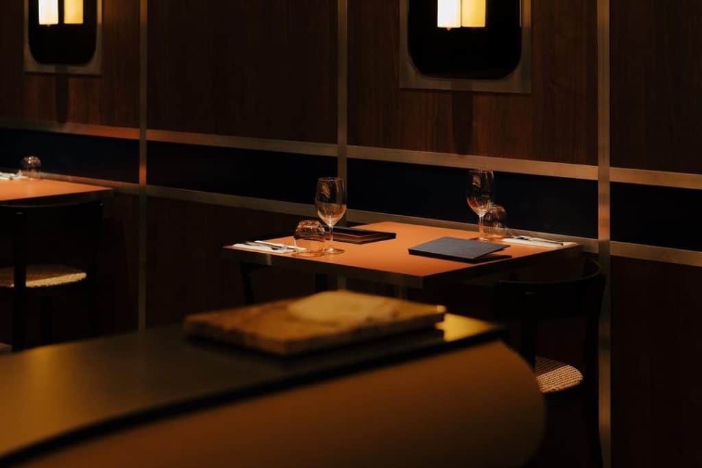 Slick moody interior with dim lighting, set table awaiting diners