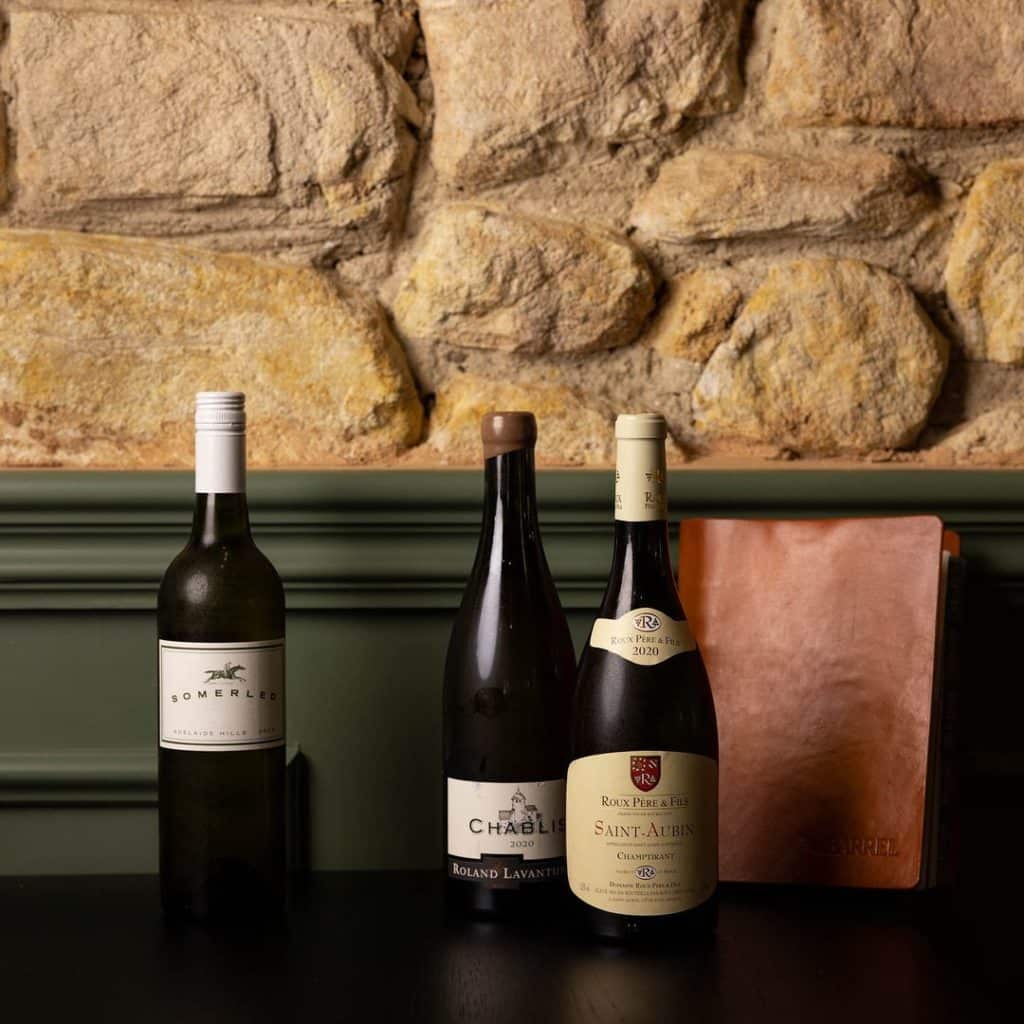 Three bottles of international wines against exposed stone wall