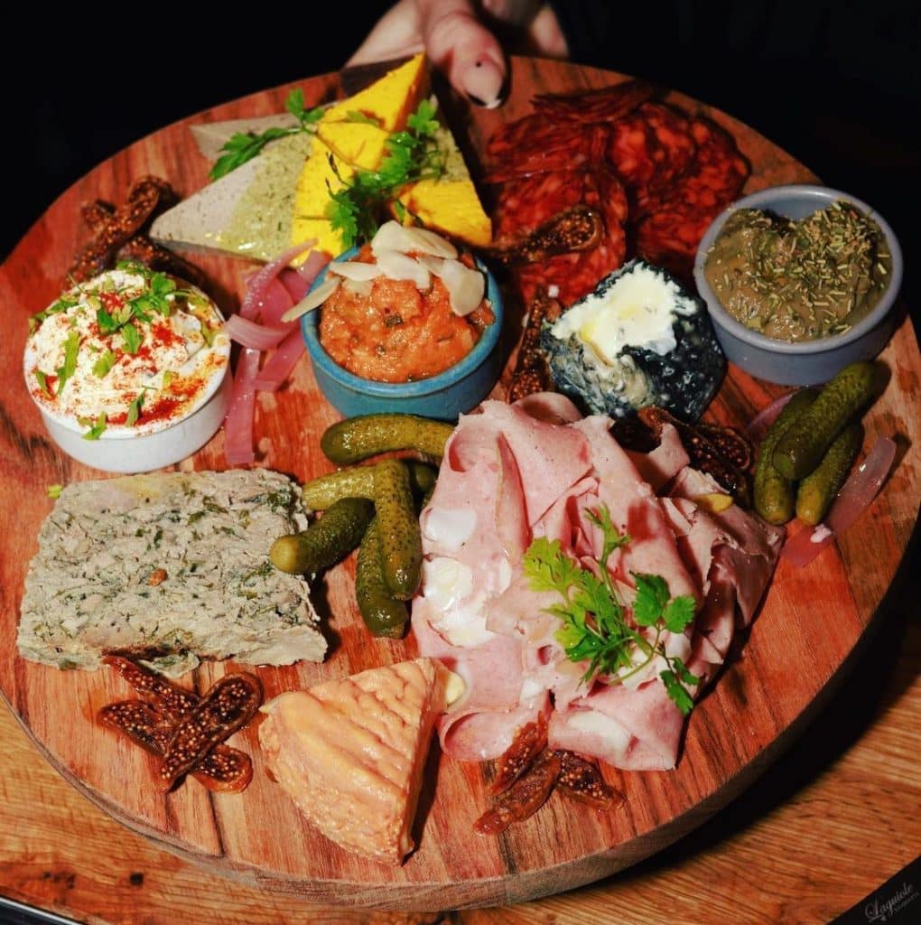 Charcutterie board filled with ham, cheeses, pickles, 