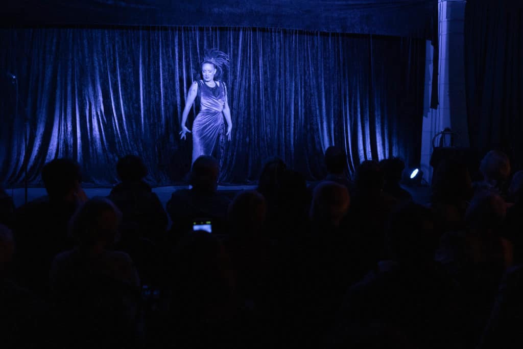 Singular performer on a stage in a darkened room