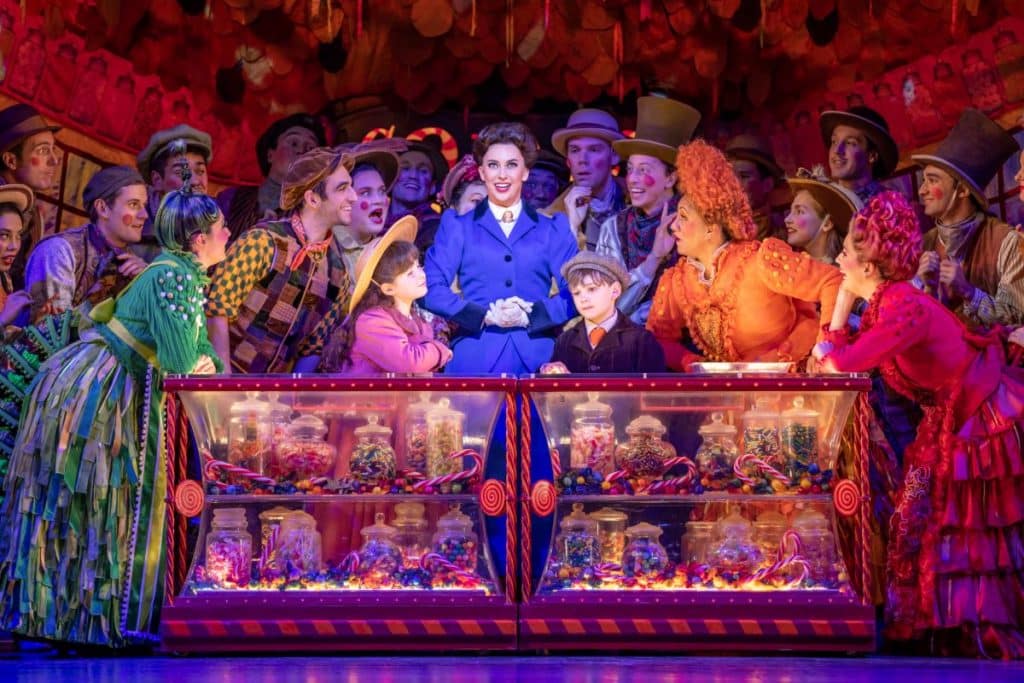 Mary Poppins cast performing in front of cabinet filled with lollies