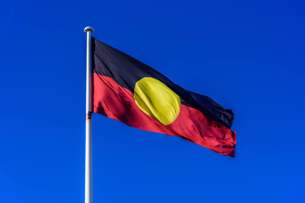 Large Aboriginal Flag at full mast against blue sky
