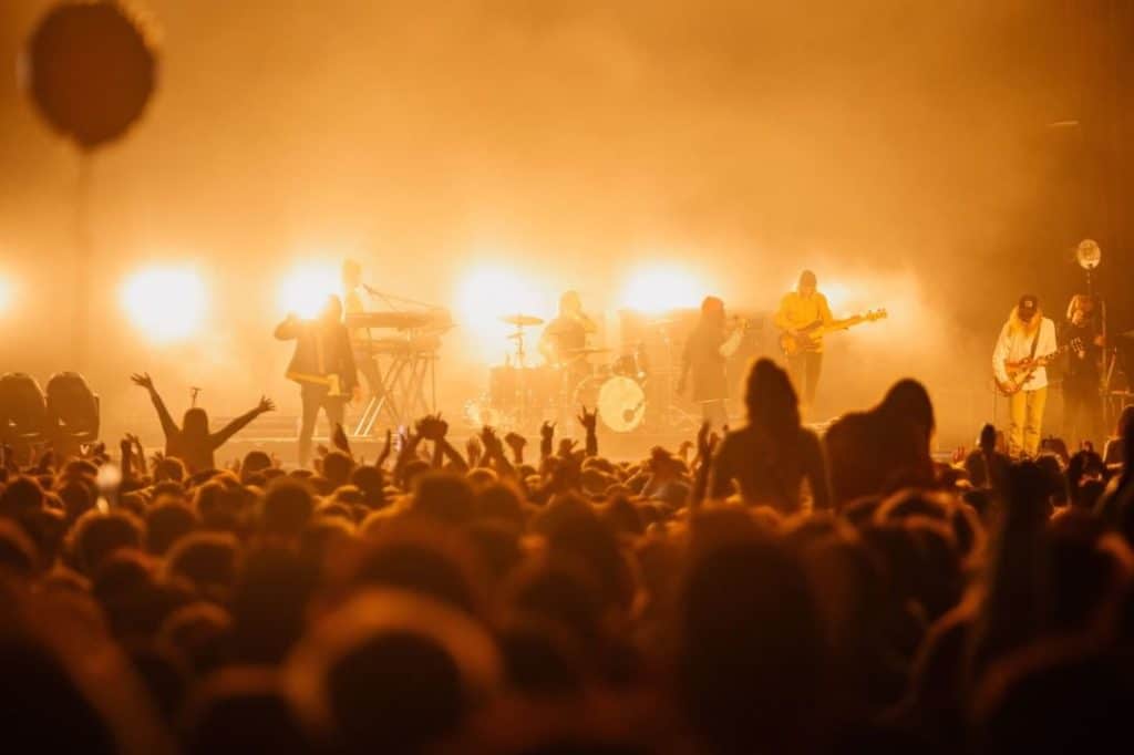 Crows at a festival, shot of the stag with six musicians playing guitars/drums with a smoky yellow haze