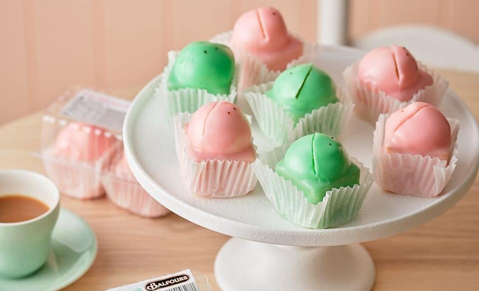 A platter of pink and green bite-sizes cakes that are shaped like frog heads