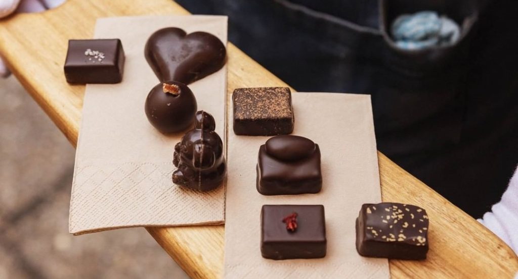 A variety of small chocolates spread across a wooden board carefully